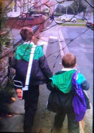 Two boys wearing matching coats walking and holding hands