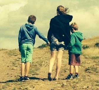 Two boys and one girl holding hands walking at beach