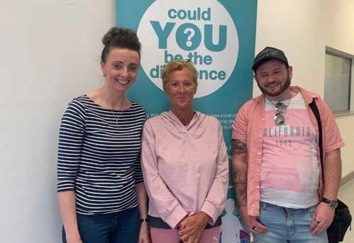 Foster carer and two members of Liverpool foster team in front of roll up banner