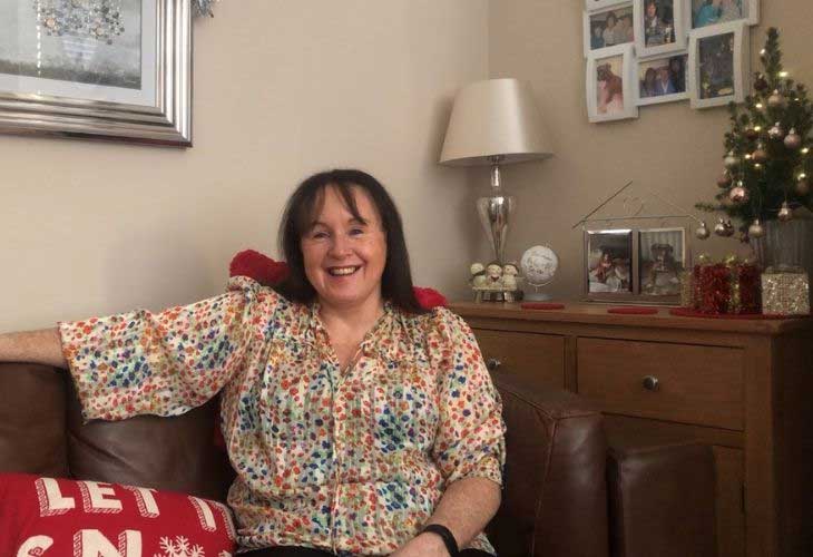 Foster carer sitting on sofa alongside christmas tree