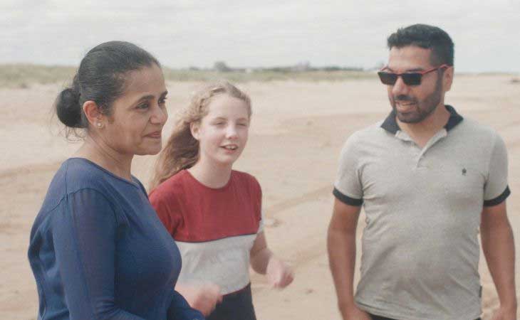 Foster parents and foster daughter walking on beach