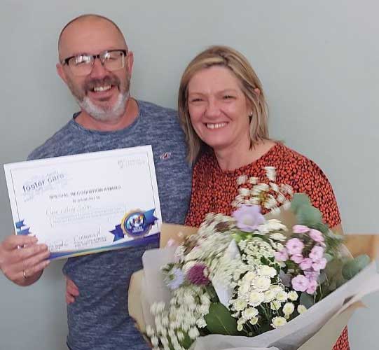 Claire and Andy foster carers receiving flowers and certificate